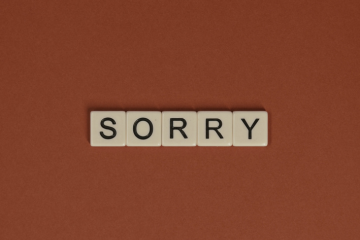 tiles spelling ''sorry'' on a rust orange background